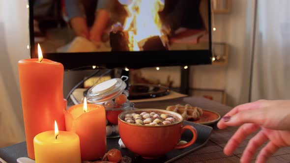 Woman Watches Tv and Drinks Cocoa on Halloween