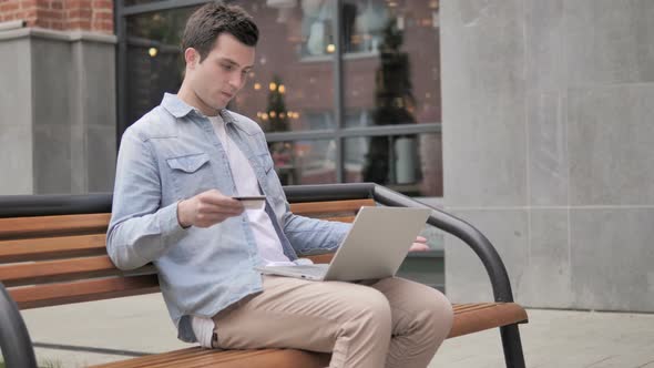 Online Shopping Failure for Young Man Sitting on Bench