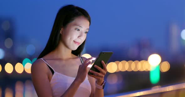 Young Woman use of mobile phone in city at night