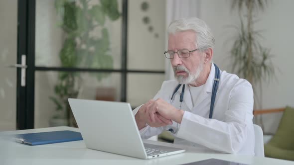 Senior Old Doctor Talking on Video Call on Laptop in Clinic