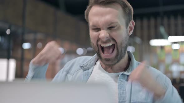 Close Up of Positive Young Man Celebrating Success at Work