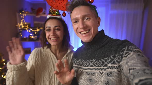 POV First Person View Happy Cheerful Excited Couple Woman in Festive Elf Cap and Man in Red Reindeer