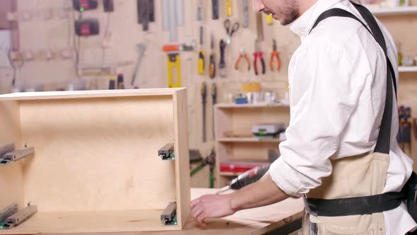 Concept of Business and Manufacture Young Man in the Workshop Assembles Furniture