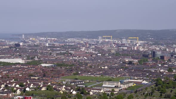 Aerial flyover of west Belfast from the countryside looking towards the city centre or center