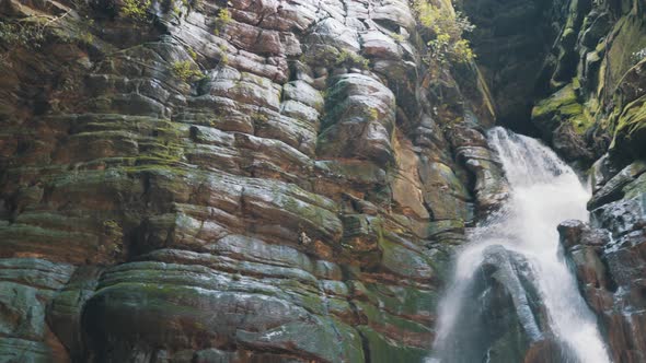 Dark cave waterfall rock wall looking up panning shot