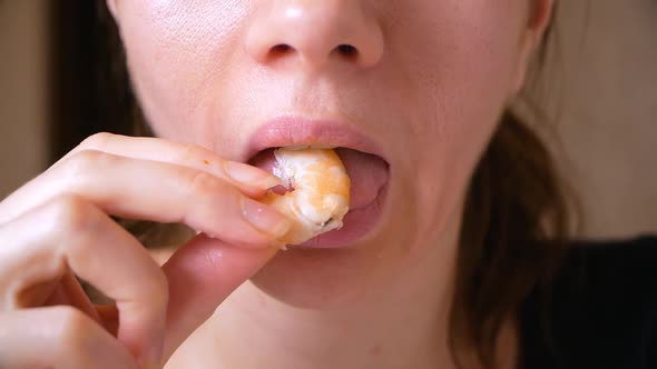 Closeup of Beautiful Young Woman Eats Boiled Shrimp. Mouth Chewing Shrimp