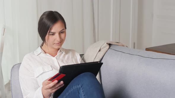 A Young Woman Uses a Tablet For Online Shopping at Home. Purchase Confirmation By the Internet.