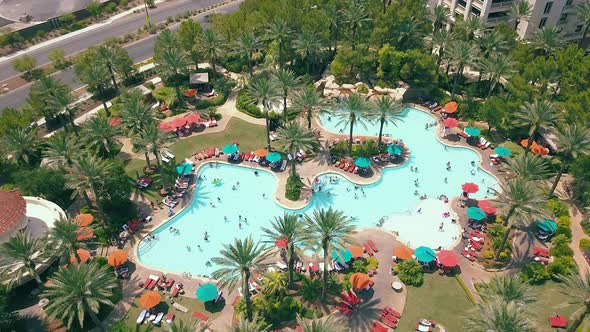 Drone footage of people enjoying a resort pool. Drone is moving counter clockwise. 4K