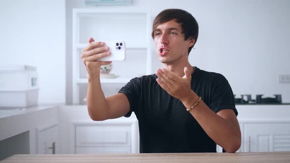 Young Man Holding Smartphone and Talking on a Video Call Using His Mobile Phone at Home in the