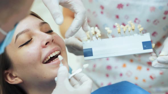 A dentist in rubber white gloves picks up the patients dentures by color.