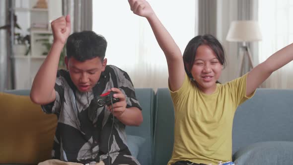 Asian Children With Joystick Game Play Video Game On Tv And Celebrating Victory