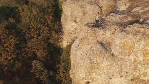 A female hiker with raised hands up at the edge of rock