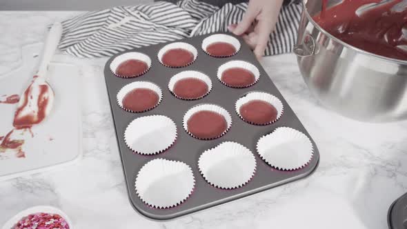 Step by step. Scooping cupcake batter into foil cupcake cups to bake red velvet cupcakes.