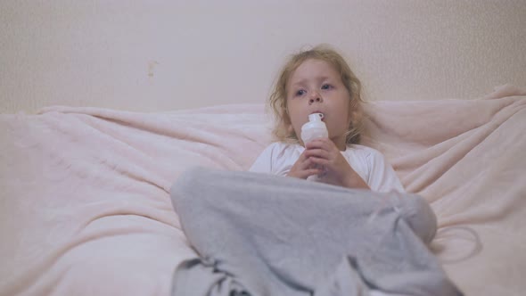 Little Girl with Inhaler Lies in Comfortable Bed in Room