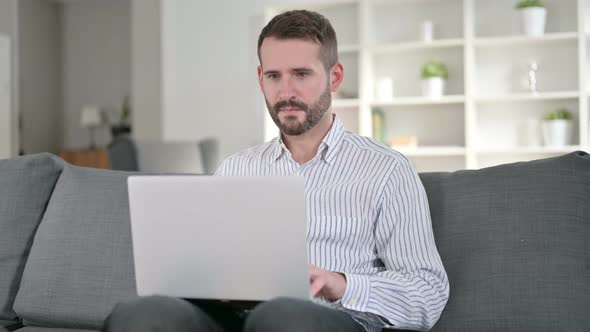 Ambitious Man Celebrating Success on Laptop at Home 