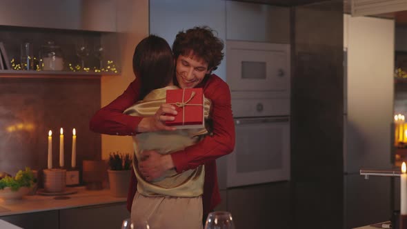 Man Embracing Woman and Giving Gift Box at Home