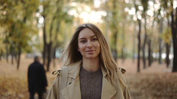 Front View of a Cheerful Woman Walking By Autumn Park