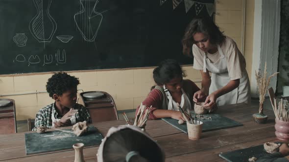Teacher Helping Kids Shaping Clay
