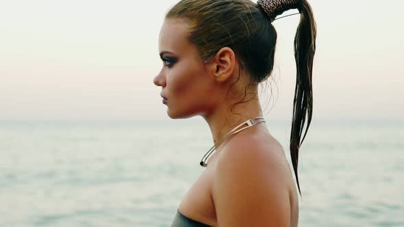 Closeup View of Sexy Woman with Professional Golden Makeup and Wet Ponytail Walking By the Water on