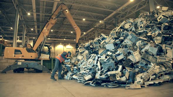 Electronic Garbage Recycling Factory. Landfill Inspector Is Examining a Pile Garbage