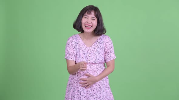 Happy Asian Pregnant Woman Laughing and Pointing at Camera