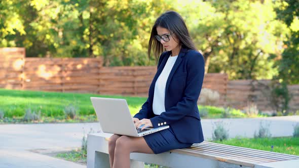 Successful Business Woman with Laptop Computer on Green Park Background