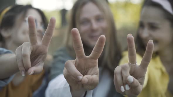 Closeup Male Female Caucasian Hands Showing Peace Gesture Blurred Hippies Smiling Talking Background