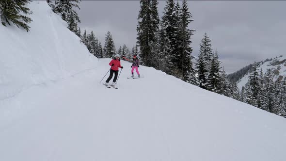 Family Of Mom And Daughter Skiers Are Having Fun Skiing Down Mountain Slope