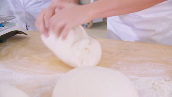 Closeup of Dough Kneaded By Baker on a Wooden Board Sprinkled with Flour