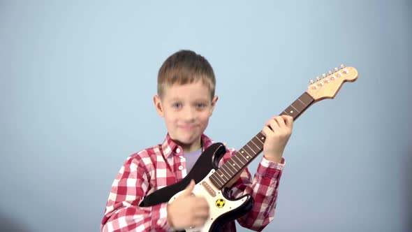 Funny Caucasian preschooler boy cheerfully depicts playing the guitar