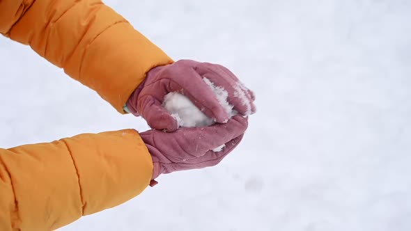 A Woman in Pink Gloves Makes Snowballs