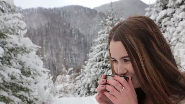 A Young Girl is Drinking Hot Tea in a Snowy Forest She is Warmed By a Drink From a Thermos