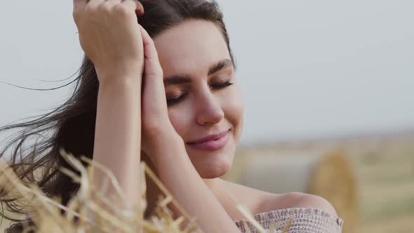 Harmonized Brunette with Blowing Hair Dreams and Smiles at Camera at Haystack