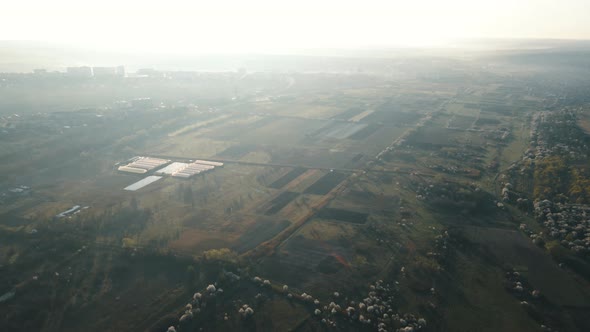 Aerial View of Agricultural Fields Near the City Suburb in the Morning at Sunrise