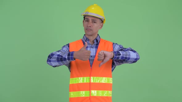 Confused Multi Ethnic Man Construction Worker Choosing Between Thumbs Up and Thumbs Down