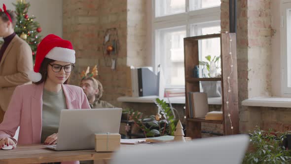 Businesswoman in Santa Hat Working in Office on Christmas