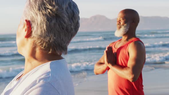 Senior african american couple practising yoga at the beach