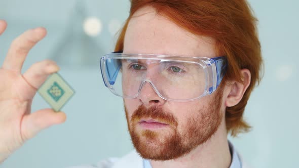 Scientist in Protective Glasses Looking at Computer Chip