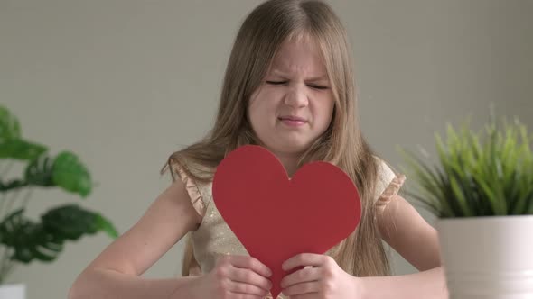 Angry Little Girl Cutting Red Paper Heart Heartbreak and Heartache Concept for Valentines Day