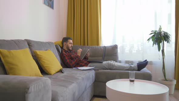 Young Man Social Distancing ,Working From Home Using Tablet and Laptop