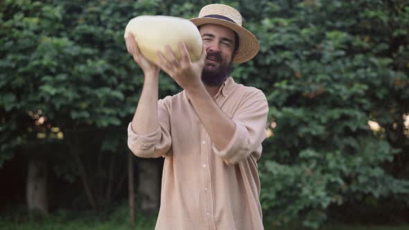 Medium Shot Portrait of Smiling Satisfied Male Farmer Juggling Big Zucchini Showing Thumb Up Looking