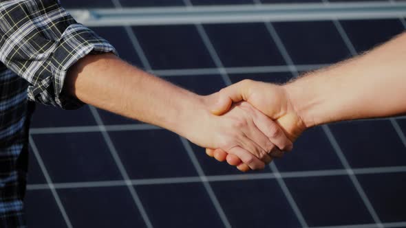 Handshake of Two Businessmen on a Background Surface of Solar Panels