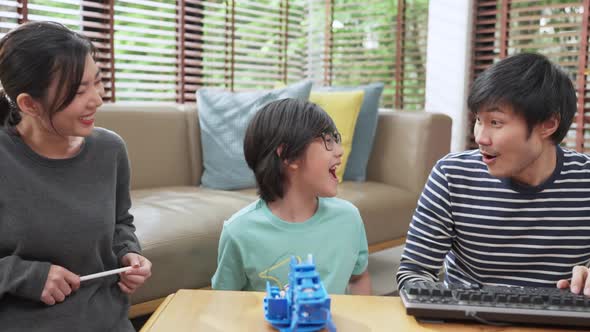 asian boy child with father mom control robot arm on Digital tablet and computer keyboard