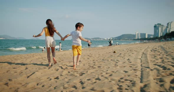 Happy Caucasian Children Run Forward Along the Beach