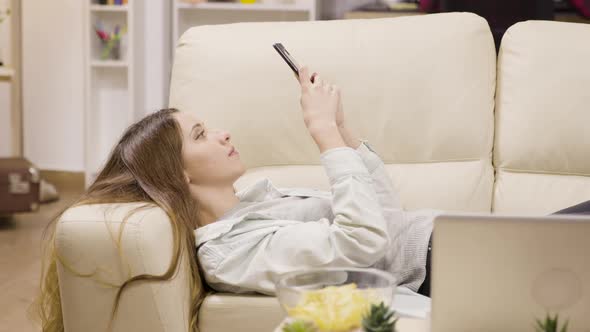 Pretty Girl Relaxing on the Couch Using Her Smartphone