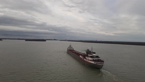 Long cargo vessel with Canada flag in Detroit river, aerial orbit view