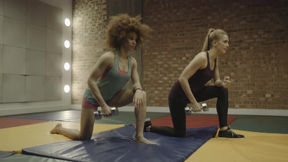 Two adult women exercising with weights in gym