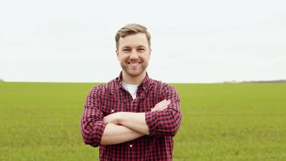 Portrait Shot of Attractive Farmer Standing in Green Field Smiling Cheerfully to Camera