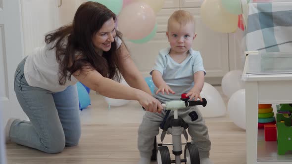 Mother and Baby Boy Play on the Floor Mother Teaches 1 Year Old Child to Ride a Balance Bike