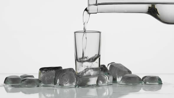 Pouring Up Shot of Vodka From a Bottle Into Glass. White Background